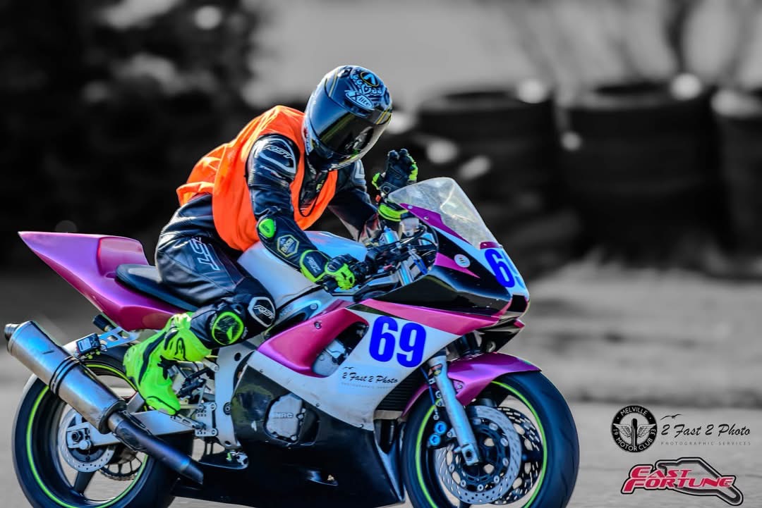 Xander riding a pink and white number 69 motorcycle, with the original photographer credits visible